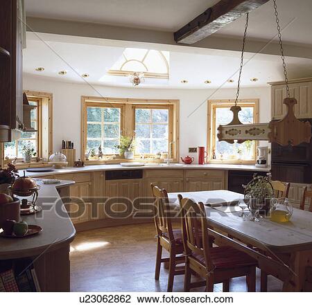 Wooden table and chairs in fitted pine country kitchen with new windows above the units View Large Photo Image Stock Image - Wooden table and chairs in fitted pine country kitchen with new windows above the units. Fotosearch