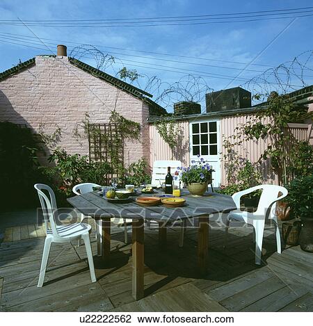 Wooden table and white plastic chairs on decking patio constructed from old wooden pallets View Large Photo Image Stock Image - Wooden table and white plastic chairs on decking patio constructed from old wooden pallets. Fotosearch