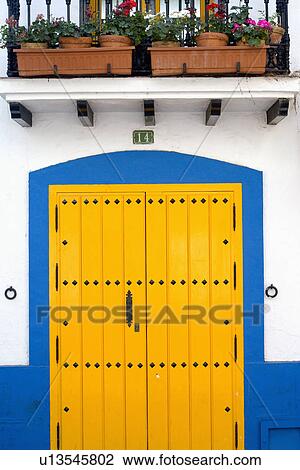 Yellow door with blue painted surround below pots on porch of Spanish townhouse View Large Photo Image Stock Image - Yellow door with blue painted surround below pots on porch of Spanish townhouse. Fotosearch