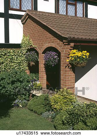 Stock Photography - Yellow pansies in hanging basket on brick porch of newbuild house. Fotosearch