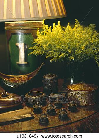 Yellow solidago in vase on table with collection of antique lacquered boxes and lighted lamp View Large Photo Image Stock Photo - Yellow solidago in vase on table with collection of antique lacquered boxes and lighted lamp. Fotosearch