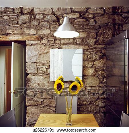 Stock Photography - Yellow sunflowers on table in cottage dining room with rough stone wall. Fotosearch