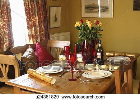 Yellow tulips in red glass vase on wooden table with Christmas crackers beside place settings View Large Photo Image Stock Photo - Yellow tulips in red glass vase on wooden table with Christmas crackers beside place settings. Fotosearch
