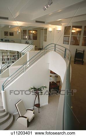 Stock Image - Aerial view of hall and staircase in openplan modern white loft conversion with green metal bannister rails. Fotosearch