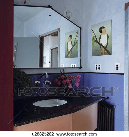 Angular mirror above underset basin in black and pink vanity unit in modern blue bathroom View Large Photo Image Stock Image - Angular mirror above underset basin in black and pink vanity unit in modern blue bathroom. Fotosearch