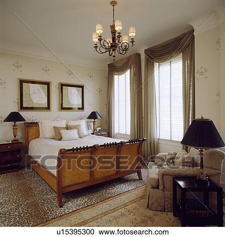 Antique bed and beige armchair in neutral bedroom with beige sheer curtains at tall windows View Large Photo Image Stock Image - Antique bed and beige armchair in neutral bedroom with beige sheer curtains at tall windows. Fotosearch