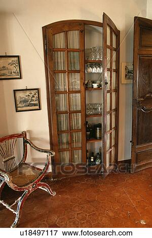 Antique chair beside alcove cupboard with glazed doors in country hall View Large Photo Image Stock Photo - Antique chair beside alcove cupboard with glazed doors in country hall. Fotosearch