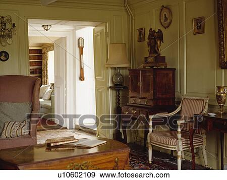 Antique desk and striped chair in cream panelled cottage livingroom with open double doors View Large Photo Image Stock Photo - Antique desk and striped chair in cream panelled cottage livingroom with open double doors . Fotosearch
