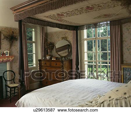 Antique four-poster bed with brown fringed top in country bedroom with French windows View Large Photo Image Stock Photo - Antique four-poster bed with brown fringed top in country bedroom with French windows. Fotosearch