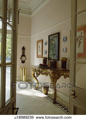 Antique gilt console table and tiled floor in traditional townhouse hall with half-glazed doors View Large Photo Image Stock Photo - Antique gilt console table and tiled floor in traditional townhouse hall with half-glazed doors. Fotosearch