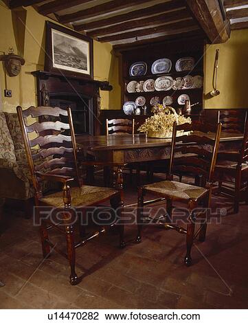 Antique table and rush-seated chairs in small country diningroom with tiled floor View Large Photo Image Stock Image - Antique table and rush-seated chairs in small country diningroom with tiled floor. Fotosearch