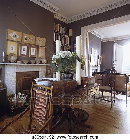 Antique table and stripped wood flooring in traditional livingroom with marble fireplace and grey walls and view through arch to sittingroom View Large Photo Image Stock Image - Antique table and stripped wood flooring in traditional livingroom with marble fireplace and grey walls and view through arch to sittingroom. Fotosearch