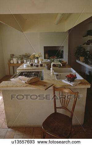 Antique wooden chair in front of island unit with oven and double sinks in French country kitchen View Large Photo Image Stock Image - Antique wooden chair in front of island unit with oven and double sinks in French country kitchen. Fotosearch