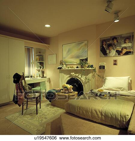 Bed with fitted quilted cover on carpetted platform in teenage bedroom with marble fireplace and Duran Duran poster View Large Photo Image Stock Photograph - Bed with fitted quilted cover on carpetted platform in teenage bedroom with marble fireplace and Duran Duran poster. Fotosearch