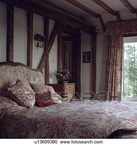 Bed with pink Toile de Jouy upholstered headboard and linen in beamed country bedroom View Large Photo Image Stock Image - Bed with pink Toile de Jouy upholstered headboard and linen in beamed country bedroom. Fotosearch