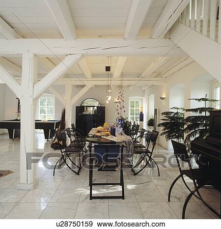 Black eighties table and chairs in dining room with white beamed ceiling and marble flooring View Large Photo Image Stock Photo - Black eighties table and chairs in dining room with white beamed ceiling and marble flooring. Fotosearch