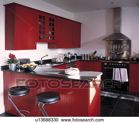 Black leather and chrome stools at breakfast bar with granite worktop in modern kitchen with red fitted cupboards View Large Photo Image Stock Image - Black leather and chrome stools at breakfast bar with granite worktop in modern kitchen with red fitted cupboards . Fotosearch