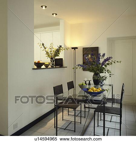 Black metal chairs and glass-topped table in modern white dining room with uplighter and recessed lighting View Large Photo Image Stock Photography - Black metal chairs and glass-topped table in modern white dining room with uplighter and recessed lighting. Fotosearch