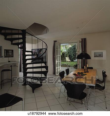 Black spiral staircase and white tiled floor in modern dining room with black and chrome chairs View Large Photo Image Picture - Black spiral staircase and white tiled floor in modern dining room with black and chrome chairs. Fotosearch