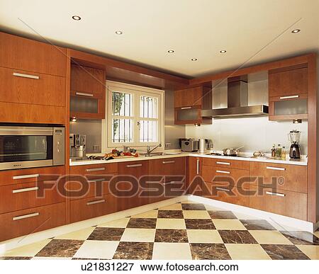 Stock Photo - Black+cream chequerboard flooring in modern kitchen with walnut fitted cupboards. Fotosearch