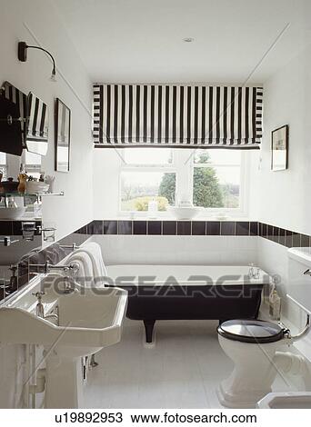Stock Photo Of Black White Striped Blind Above Rolltop Bath In Black White Striped Blind Above Rolltop Bath In Bathroom With Tiled Border On Wall