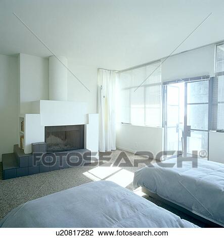 Blue duvets on single beds in modern city bedroom with white fireplace View Large Photo Image Stock Image - Blue duvets on single beds in modern city bedroom with white fireplace. Fotosearch
