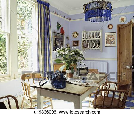 Blue fringed lampshade above radio and handbag on small table in pastel blue dining room View Large Photo Image Stock Photograph - Blue fringed lampshade above radio and handbag on small table in pastel blue dining room. Fotosearch