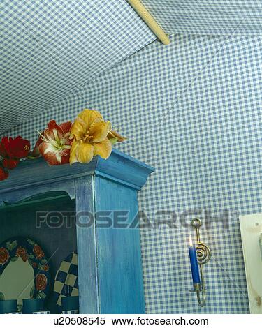 Stock Photography - Blue painted cupboard against blue check fabric-covered walls of garden shed. Fotosearch