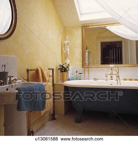 Blue rolltop bath below gilt mirror in attic bathroom with ragging-effect walls View Large Photo Image Stock Photo - Blue rolltop bath below gilt mirror in attic bathroom with ragging-effect walls. Fotosearch