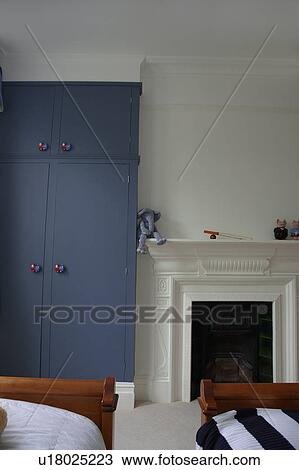 Blue storage cupboard and traditional white fireplace in modern white bedroom View Large Photo Image Stock Image - Blue storage cupboard and traditional white fireplace in modern white bedroom. Fotosearch