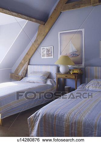 Blue+beige striped bedlinen on twin beds in pastel blue attic bedroom View Large Photo Image Stock Photograph - Blue+beige striped bedlinen on twin beds in pastel blue attic bedroom. Fotosearch