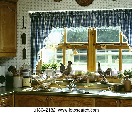 Blue+white checked curtains above chicken ornaments on window sill above wooden drainer and steel sink View Large Photo Image Stock Image - Blue+white checked curtains above chicken ornaments on window sill above wooden drainer and steel sink. Fotosearch