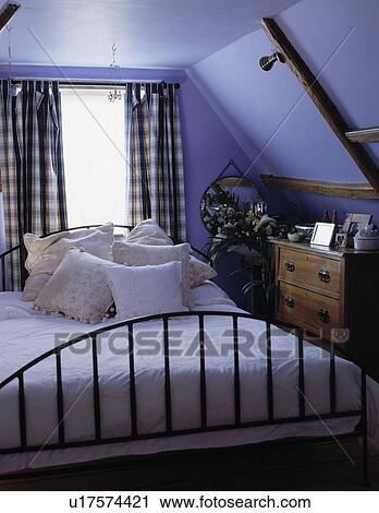 Blue+white checked curtains on window behind iron bed with white cushions and bedcover in blue attic bedroom View Large Photo Image Stock Image - Blue+white checked curtains on window behind iron bed with white cushions and bedcover in blue attic bedroom. Fotosearch