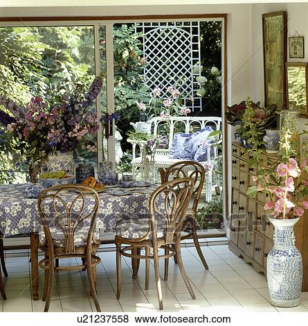 Blue White Cloth On Table In Dining Room With Bentwood Chairs And Open Patio Doors With View Of The Garden Stock Photo U21237558 Fotosearch