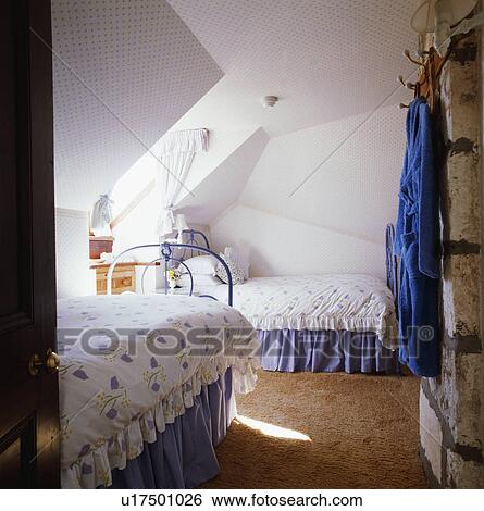Stock Photograph - Blue+white duvets on twin beds with blue vallances in white attic bedroom. Fotosearch