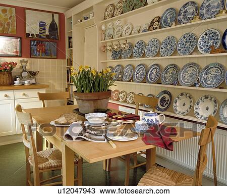 Blue+white plates on white shelves in dining room with table set for breakfast and daffodils in pot View Large Photo Image Stock Image - Blue+white plates on white shelves in dining room with table set for breakfast and daffodils in pot. Fotosearch