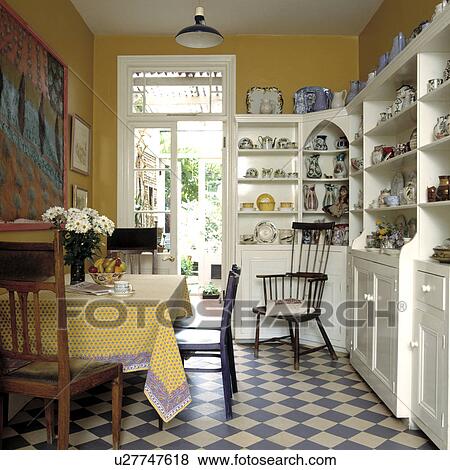 Blue+white tiled floor and built-in white shelving and cupboards in yellow dining room with yellow cloth on table View Large Photo Image Stock Photo - Blue+white tiled floor and built-in white shelving and cupboards in yellow dining room with yellow cloth on table. Fotosearch