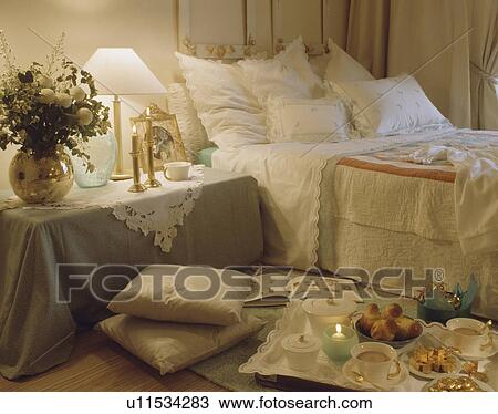 Breakfast tray on floor beside bed piled with white cushions in traditional bedroom with grey cloth on bedside table View Large Photo Image Stock Image - Breakfast tray on floor beside bed piled with white cushions in traditional bedroom with grey cloth on bedside table. Fotosearch