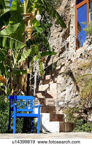 Stock Photo - Bright blue chair beside steps to door of traditional stone house in Spain. Fotosearch