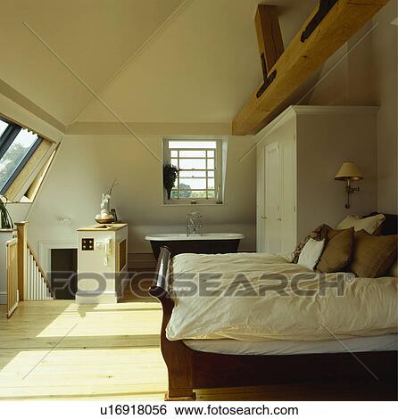Brown cushions and cream duvet on lit bateau bed in modern loft conversion bedroom with open ensuite bathroom View Large Photo Image Stock Photograph - Brown cushions and cream duvet on lit bateau bed in modern loft conversion bedroom with open ensuite bathroom. Fotosearch