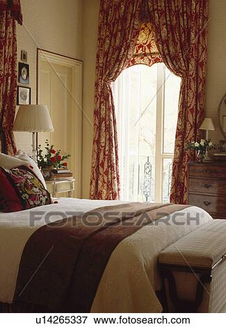 Brown wool throw on bed in townhouse bedroom with red patterned curtains and matching blind at French doors View Large Photo Image Stock Photo - Brown wool throw on bed in townhouse bedroom with red patterned curtains and matching blind at French doors. Fotosearch