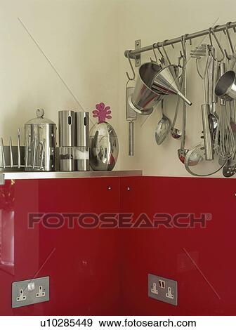 Canisters and stainless steel utensils on rail storage above red kitchen unit with electric plug sockets View Large Photo Image Stock Photo - Canisters and stainless steel utensils on rail storage above red kitchen unit with electric plug sockets. Fotosearch