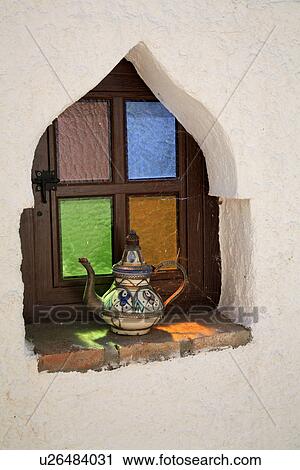 Stock Image - Ceramic coffee pot on windowsill of Moorish window with stained glass. Fotosearch