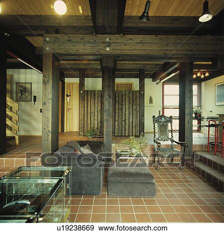 Ceramic floor tiles and grey velour sofa in openplan living room with beamed ceiling View Large Photo Image Stock Photo - Ceramic floor tiles and grey velour sofa in openplan living room with beamed ceiling. Fotosearch