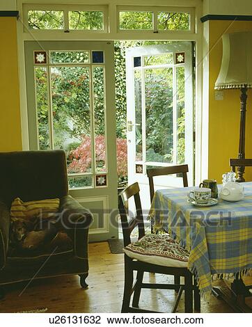 Checked cloth on table in diningroom with green armchair beside open French doors with stained glass detail View Large Photo Image Stock Image - Checked cloth on table in diningroom with green armchair beside open French doors with stained glass detail. Fotosearch