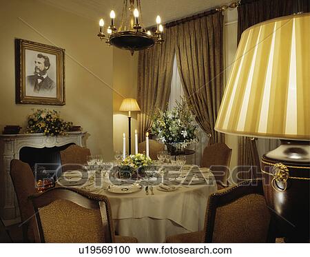 Circular table set for dinner in cosy hotel dining room with lighted lamps and fireplace View Large Photo Image Stock Image - Circular table set for dinner in cosy hotel dining room with lighted lamps and fireplace. Fotosearch