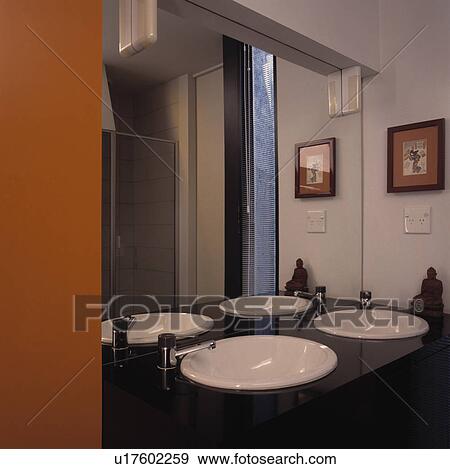 Circular white basins built into black vanity unit below mirrored wall View Large Photo Image Stock Photo - Circular white basins built into black vanity unit below mirrored wall. Fotosearch
