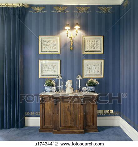 Classical bust on marble-topped cupboard below pictures and wall lights in dining room with blue striped wallpaper View Large Photo Image Stock Image - Classical bust on marble-topped cupboard below pictures and wall lights in dining room with blue striped wallpaper. Fotosearch