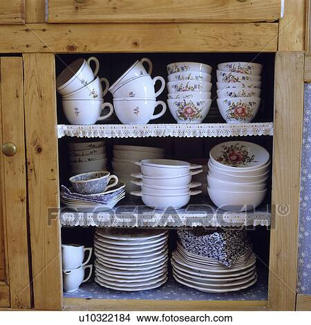 Picture - Close-up of antique china cups and bowls with plates on lace-trimmed shelves. Fotosearch