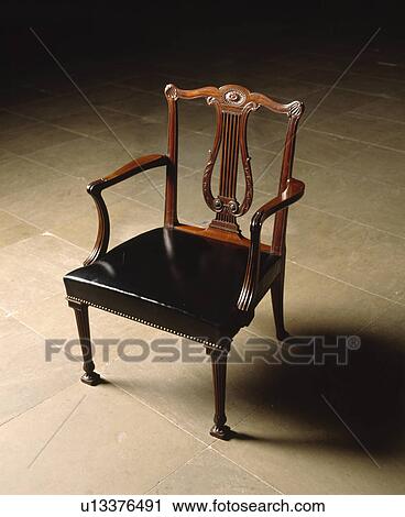 Stock Image - Close up of antique lyre back chair with upholstered black leather seat. Fotosearch